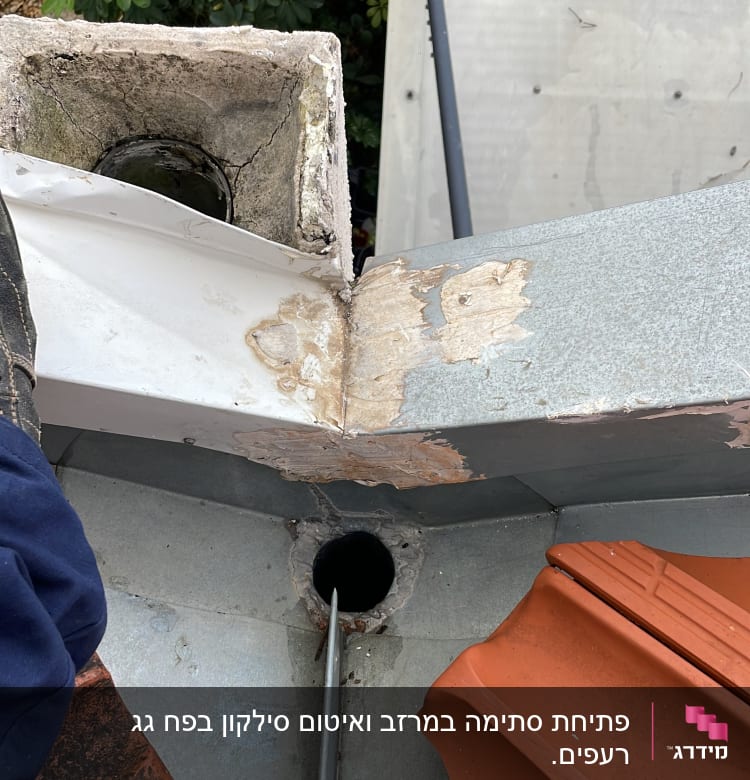 צינור מתכת נכנס לפתח ניקוז בגג